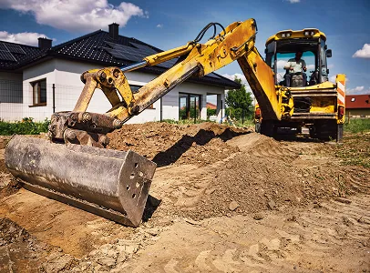 Chargeuse-pelleteuse jaune travaillant sur un chantier de construction devant une maison moderne à Corme-Royal en Charente-Maritime 17