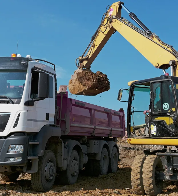 Excavatrice chargeant de la terre dans un camion-benne sous un ciel bleu clair à Corme-Royal en Charente-Maritime 17